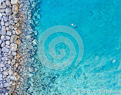 Aerial shot of a person swimming in the sea surrounded by rocks in Protaras, Cyprus Editorial Stock Photo