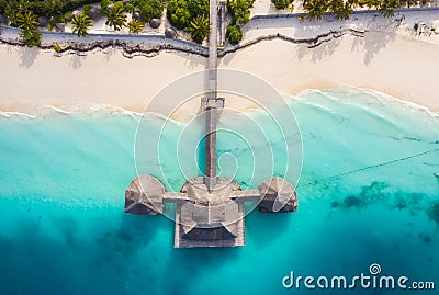 Aerial shot of the Stilt hut with palm thatch roof washed with turquoise Indian ocean waves on the white sand sandbank beach on Stock Photo