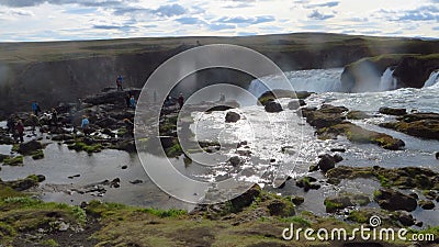 Aerial shot of tourist gathered in front of a waterfall in a mountainous area Stock Photo