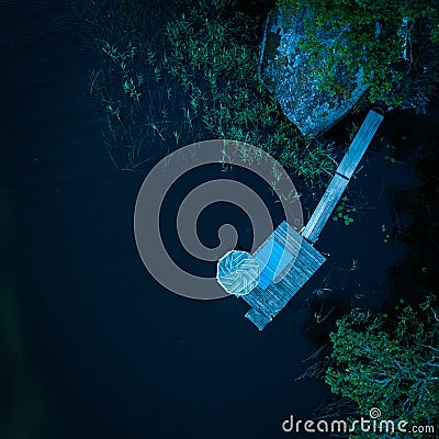 Aerial shot of a wooden landing stage in the middle of a dark lake Stock Photo