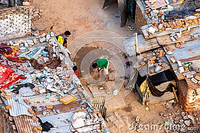 Aerial shot of young boy cleaning up the dirt path between the brick and tin slum houses with a broom Editorial Stock Photo