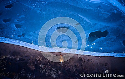 Aerial top view from above of lonesome car at frozen sea coastline with headlights on. Lonely road trip traveller enjoys Stock Photo