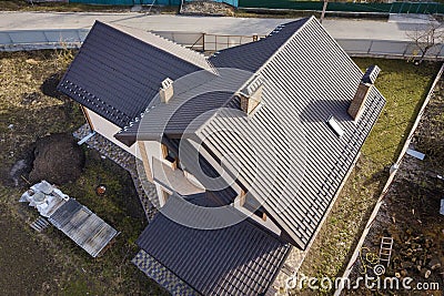 Aerial top view of building steep shingle roof, brick chimneys and small attic window on house top with metal tile roof. Roofing, Stock Photo