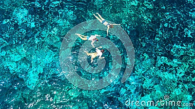 Aerial top view of family snorkeling from above, mother and kids snorkelers swimming in a clear tropical sea water with corals Stock Photo