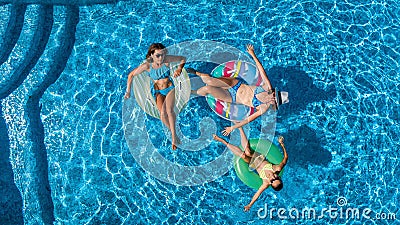 Aerial top view of family in swimming pool from above, happy mother and kids swim on inflatable ring donuts and have fun in water Stock Photo