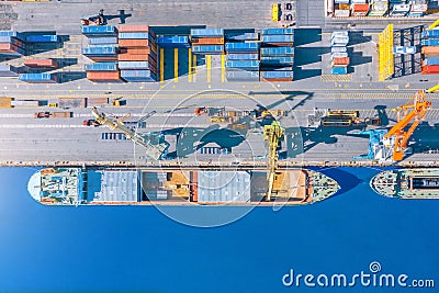 Aerial top view huge cargo ship moored at the pier at the port, loading goods, metal, concrete and other solid raw materials Stock Photo