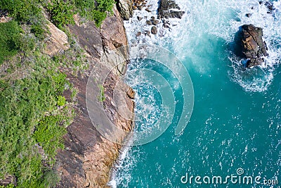 Aerial top view of ocean`s beautiful waves and rocky coast with greenery Stock Photo
