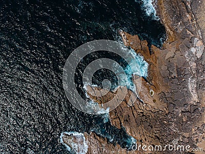 Aerial top view of sea waves hitting rocks on the beach with turquoise sea water. Amazing rock cliff seascape in the Portuguese co Stock Photo