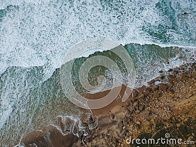 Aerial top view of sea waves hitting rocks on the beach with turquoise sea water. Amazing rock cliff seascape in the Portuguese co Stock Photo