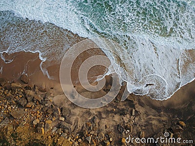 Aerial top view of sea waves hitting rocks on the beach with turquoise sea water. Amazing rock cliff seascape in the Portuguese co Stock Photo