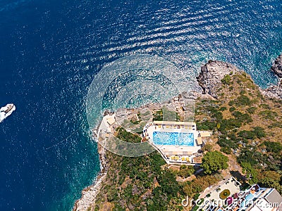 Aerial top view. Villa with a swimming pool by the sea. Steep rocky shore. Tourism and vacation concept. The motor boat moves fast Stock Photo