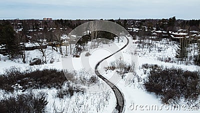 Aerial top view of a winding foot path in winter , surrounded by snow. Kanata neighborhood can be seen in the background Stock Photo