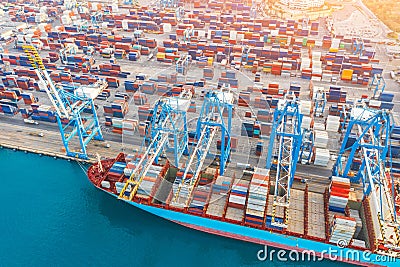 Aerial tope view - heavy huge ship with a lot of containers moored at the pier in the port, loading with cranes in the industrial Stock Photo