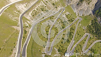 AERIAL: Tourist car driving up a winding asphalt road in the sunny Dolomites. Stock Photo