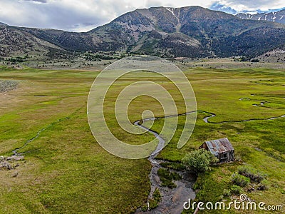 Aerial view of abandoned little small wooden house in the green valley of a mountain Stock Photo