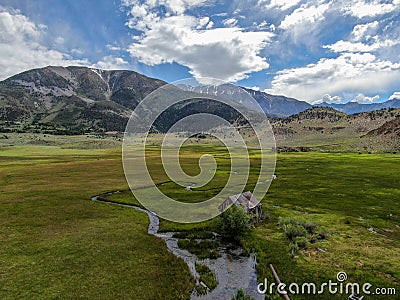 Aerial view of abandoned little small wooden house in the green valley of a mountain Stock Photo