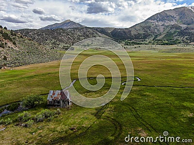 Aerial view of abandoned little small wooden house in the green valley of a mountain Stock Photo