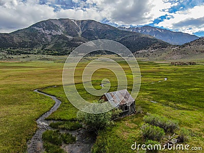 Aerial view of abandoned little small wooden house in the green valley of a mountain Stock Photo