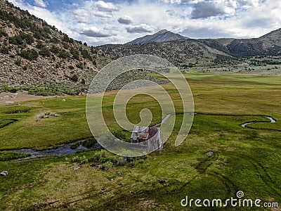 Aerial view of abandoned little small wooden house in the green valley of a mountain Stock Photo