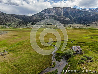 Aerial view of abandoned little small wooden house in the green valley of a mountain Stock Photo