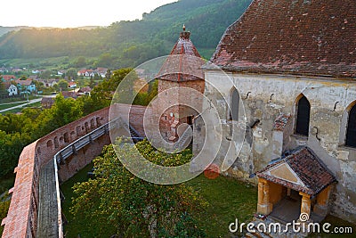 Aerial view of Alma Vii fortified church, with sun flare, at sunset. Typical fortification in Transylvania region, Romania. Stock Photo