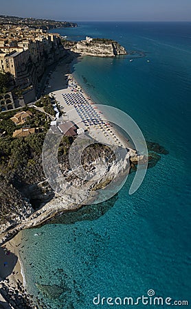 Aerial view of a beach with umbrellas and bathers. Houses on the rock and beach. Promontory. Tropea, Calabria, Italy. Stock Photo