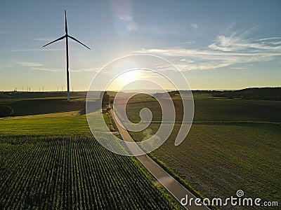 Aerial view of a landscape with agriculture fields, a road and a wind turbine on a sunny evening in summer Stock Photo