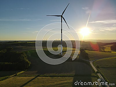 Aerial view of a landscape with agriculture fields, a road and a wind turbine on a sunny evening in summer Stock Photo