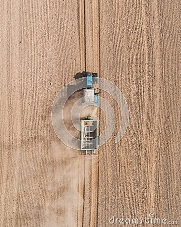 Aerial view of a blue tractor working in a field with a fertilizer and seed spreader Stock Photo