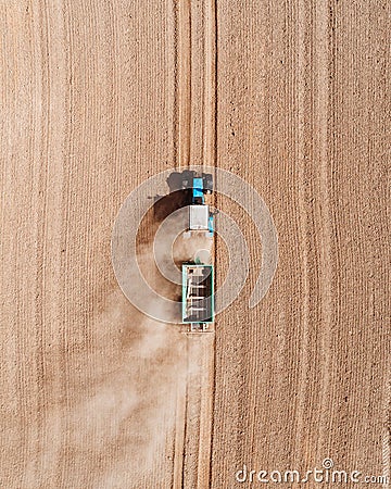 Aerial view of a blue tractor working in a field with a fertilizer and seed spreader Stock Photo