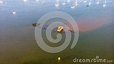 An aerial view of a boat wreck on a sandbank in an harbor at low tide surrounded by other boats under a majestic cloudy blue sky Stock Photo