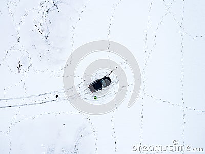 Aerial view of a car parked on a snowy field covered in footprints in winter Stock Photo