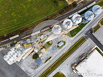 Aerial view of a cargo train by a farm with tall grain elevators and tanks in Delaware Stock Photo