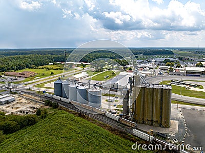 Aerial view of a cargo train by a farm with tall grain elevators and tanks in Delaware Stock Photo