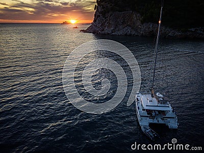 Aerial view of a cliff overlooking the sea and a catamaran moored at sunset, boat. Buljarica Beach. Montenegro Stock Photo