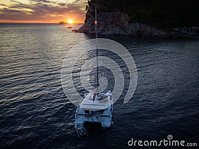 Aerial view of a cliff overlooking the sea and a catamaran moored at sunset, boat. Buljarica Beach. Montenegro Stock Photo