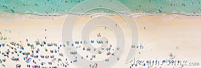 Aerial view crowded public beach with colourful umbrellas, Aerial view of sandy beach with tourists swimming in beautiful clear Stock Photo