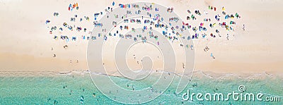 Aerial view crowded public beach with colourful umbrellas, Aerial view of sandy beach with tourists swimming in beautiful clear Stock Photo