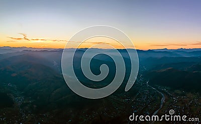 Aerial view of dark mountain hills at sunset. Hazy peaks and misty valleys in evening Stock Photo