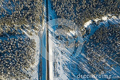 Aerial view of a direct asphalt road vertically in the mountains with conifers in winter with snow. Picturesque places and Stock Photo