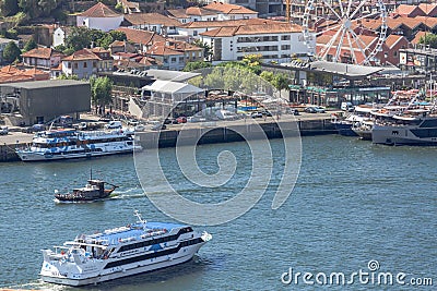 Aerial view at the Douro river, with cruisers and recreative boats, Gaia downtown buildings and ferris wheel as background Editorial Stock Photo