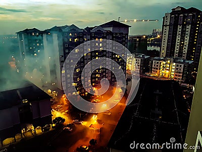 Aerial view of dramatic scene below which looked like buildings are on fire due to lights reflected on foggy evening. Stock Photo