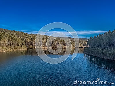 Aerial view of drone, forest with lake in mountain with wind turbines on ridge Stock Photo