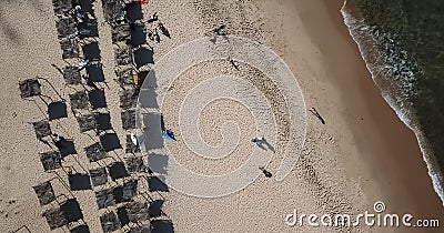 Aerial view, drone shot on the coast of Angola, people resting and playing on beach sand, surf boards on thatched huts Stock Photo