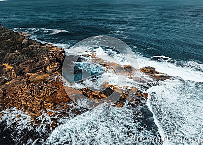Aerial view early morning light with ocean waves flowing over rocks around North Curl Curl ocean rock pool during storm. Stock Photo