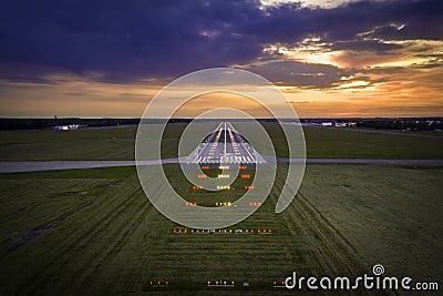 Aerial view on empty airport runaway with markings for landings and all navigation lights ILS Cat II on at the colorful sunset Stock Photo