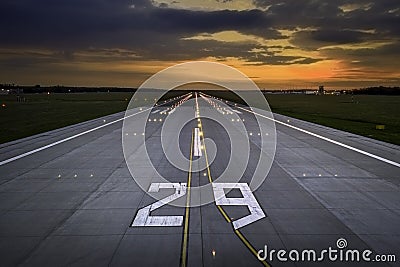 Aerial view on empty airport runaway with markings for landings, designation 29 and all navigation lights on at colorful sunset Stock Photo