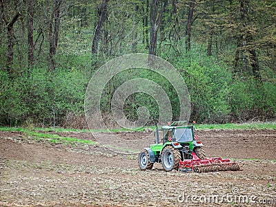 Farm tractor harrowing arable field Stock Photo