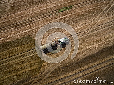 Aerial view of a farming tractor with a trailer fertilizes a freshly plowed agriculural field with manure Stock Photo