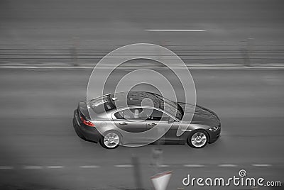 Aerial view of fast moving shiny gray car on the road. speeding in the city concept. desaturated colours and red brake lights Stock Photo